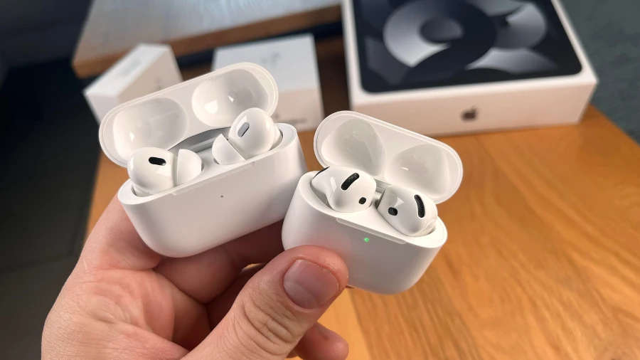 Geöffnetes Ladecase mit AirPods 4 und geöffnetes Ladecase mit AirPods Pro 2 in einer Hand.