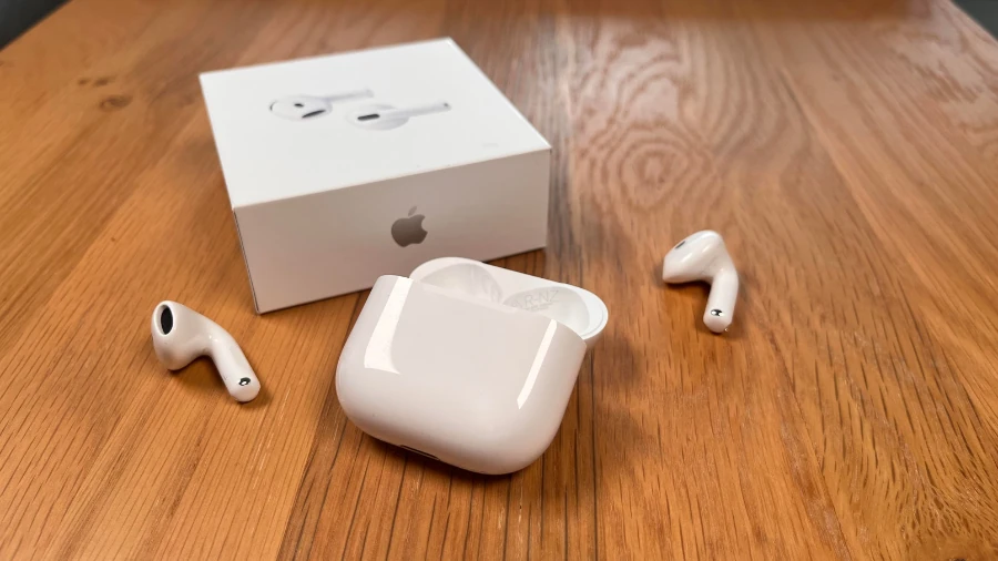 AirPods 4 und geöffnetes AirPods 4 Ladecase mit Originalverpackung auf einem Holztisch.