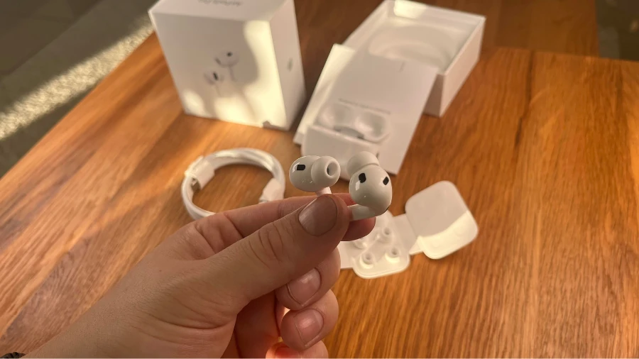 Zwei AirPods zwischen den Fingern haltend