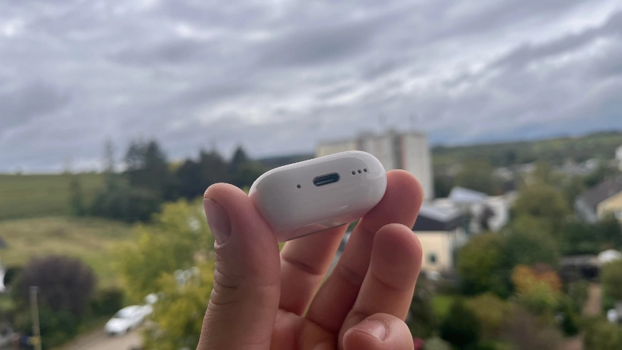 AirPods 4 Ladecase von unten mit USB-C Anschluss und Lautsprechern in der Hand.